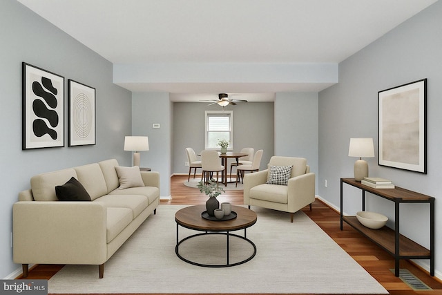 living area featuring baseboards, a ceiling fan, wood finished floors, and visible vents