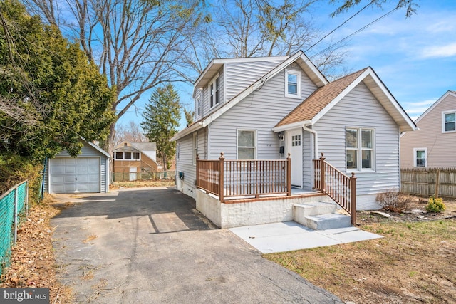 view of front of house featuring an outbuilding, fence, driveway, roof with shingles, and a detached garage