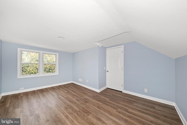 additional living space featuring baseboards, dark wood-style flooring, and vaulted ceiling