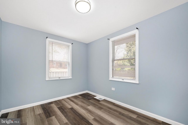 spare room with dark wood-style floors, plenty of natural light, and baseboards