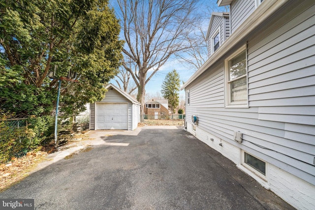 exterior space with an outbuilding, aphalt driveway, a detached garage, and fence