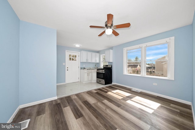 unfurnished living room featuring wood finished floors, baseboards, visible vents, and ceiling fan