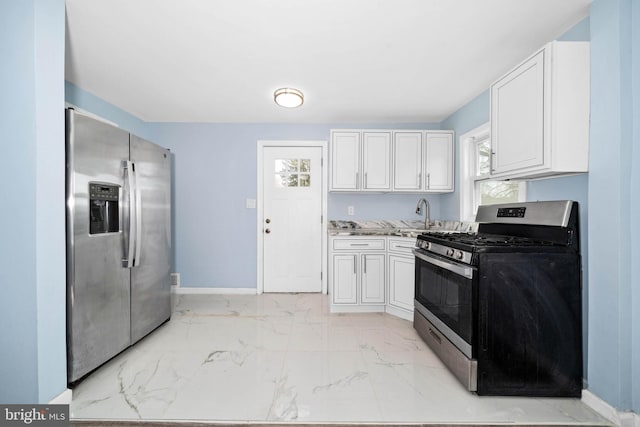 kitchen featuring baseboards, a sink, stainless steel appliances, white cabinets, and marble finish floor