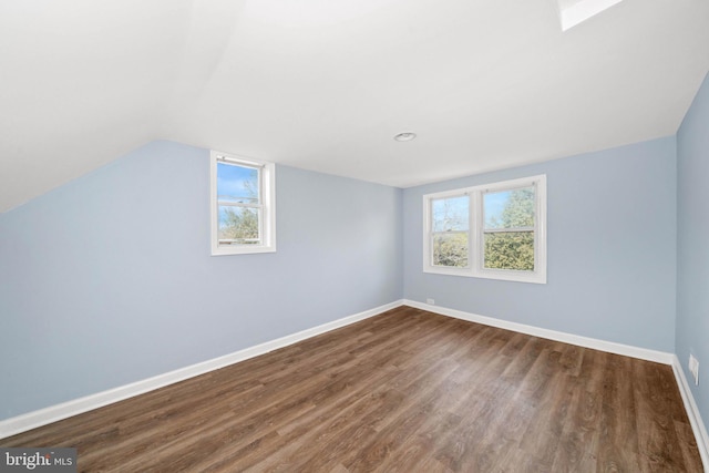 additional living space with baseboards, dark wood-type flooring, and lofted ceiling