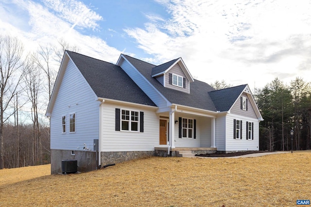 view of front of house with central AC unit, a shingled roof, and a front lawn