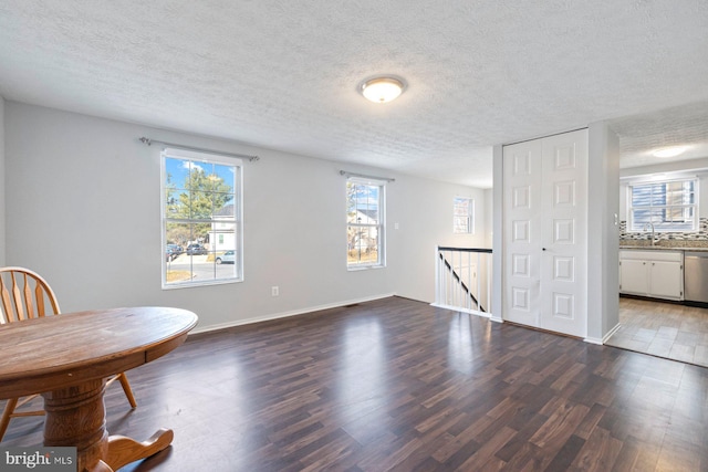 interior space featuring a textured ceiling, dark wood-type flooring, and baseboards