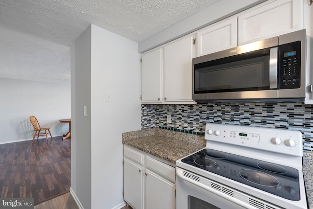 kitchen with white range with electric stovetop, stainless steel microwave, white cabinets, and backsplash