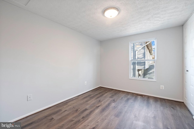 empty room featuring baseboards, a textured ceiling, and dark wood-style floors