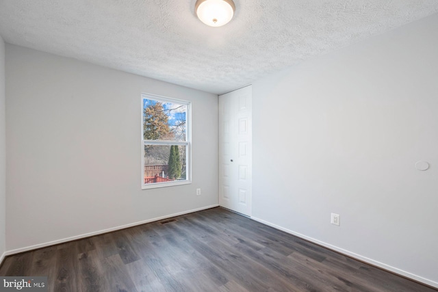 empty room with visible vents, a textured ceiling, baseboards, and dark wood-style flooring