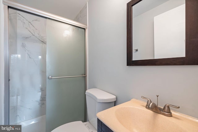 bathroom with toilet, vanity, and a shower with shower door