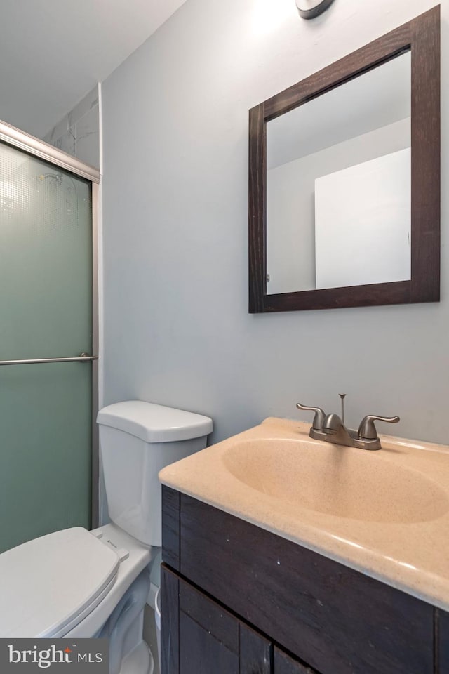 bathroom featuring vanity, a shower stall, and toilet