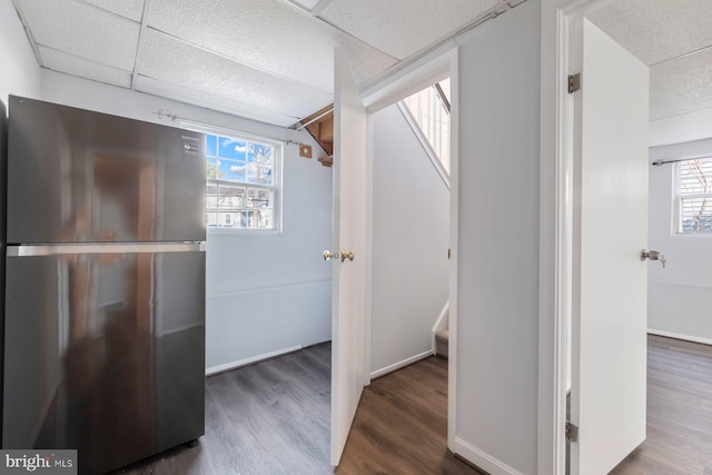 interior space with baseboards, a paneled ceiling, wood finished floors, and stairs