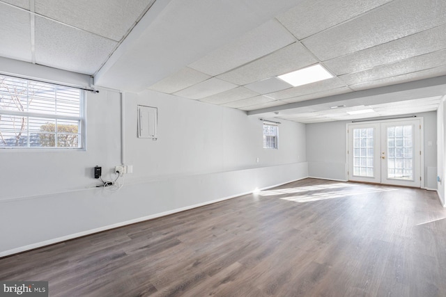 spare room featuring a drop ceiling, baseboards, wood finished floors, and french doors