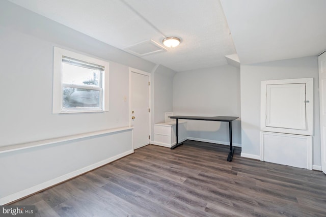 spare room featuring baseboards, dark wood-type flooring, and attic access