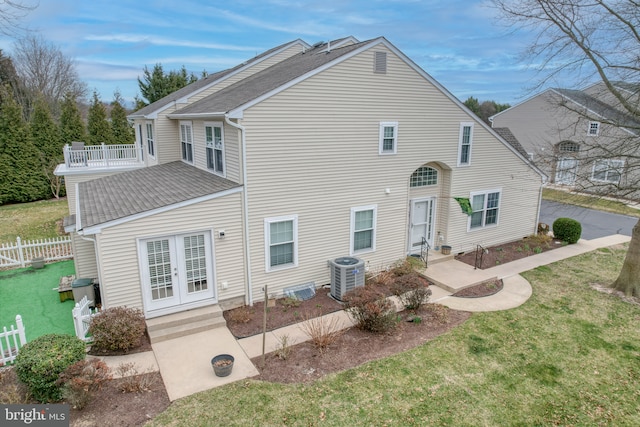 back of house with fence, central AC unit, a lawn, and a shingled roof