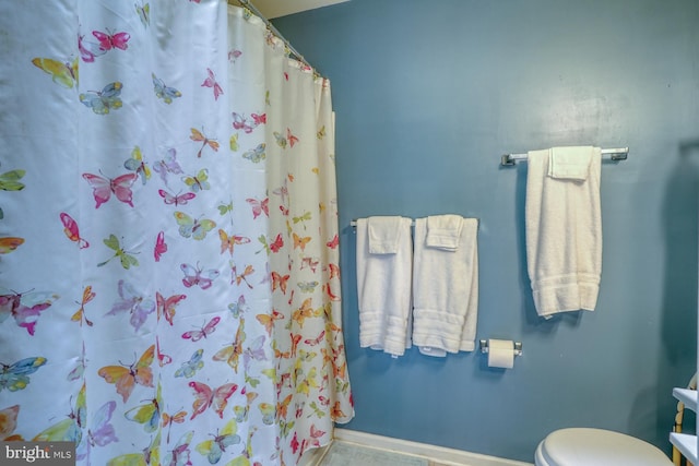 bathroom with a shower with shower curtain, baseboards, and toilet