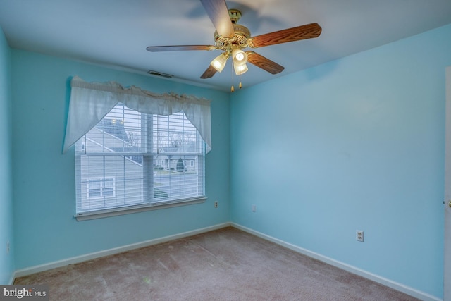 spare room featuring carpet flooring, baseboards, visible vents, and ceiling fan