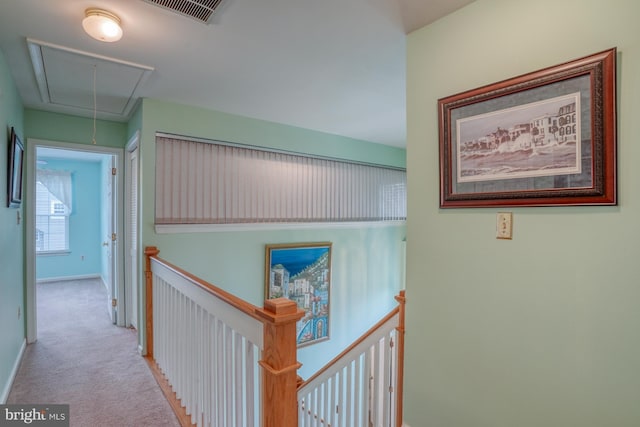 hall with visible vents, an upstairs landing, attic access, and carpet flooring