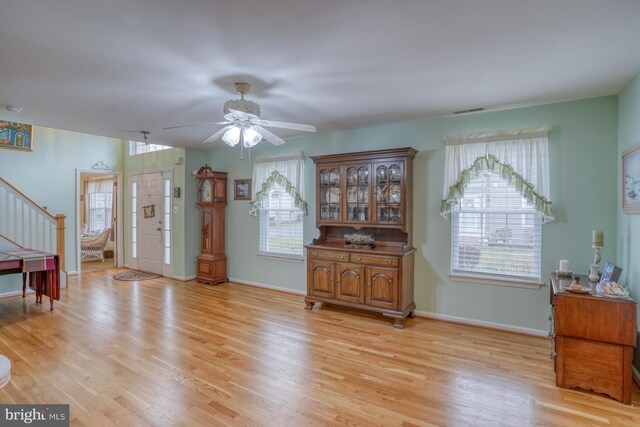 dining area featuring visible vents, light wood-style flooring, a ceiling fan, baseboards, and stairs