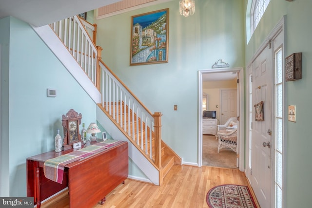 foyer entrance featuring stairway, wood finished floors, baseboards, and a towering ceiling