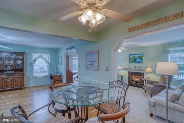 dining space featuring wood finished floors, a fireplace, baseboards, and ceiling fan