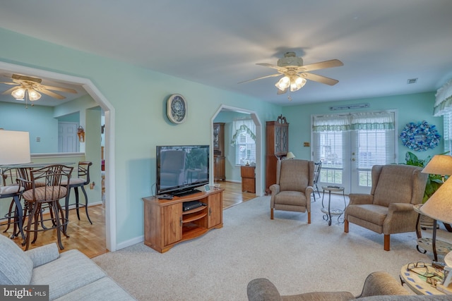 carpeted living area featuring visible vents, arched walkways, baseboards, and ceiling fan