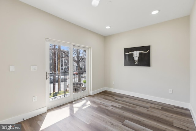 spare room with wood finished floors, a healthy amount of sunlight, and baseboards