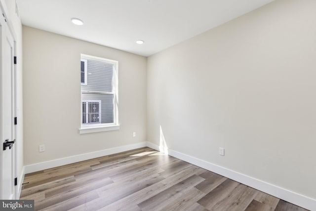 empty room with recessed lighting, wood finished floors, and baseboards