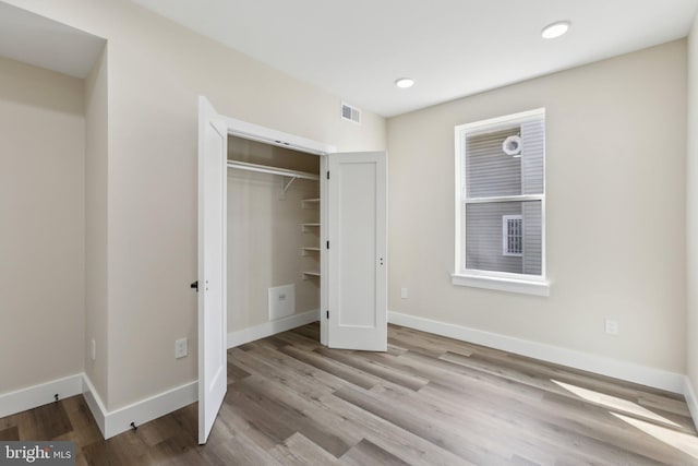 unfurnished bedroom with visible vents, baseboards, a closet, and wood finished floors