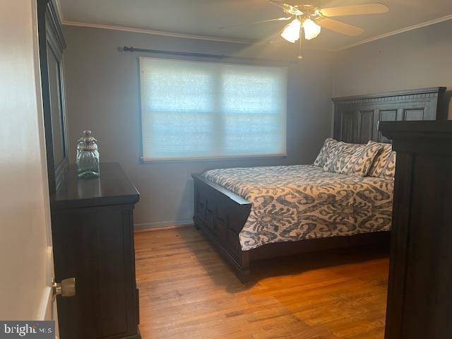 bedroom with light wood-type flooring, baseboards, ceiling fan, and crown molding