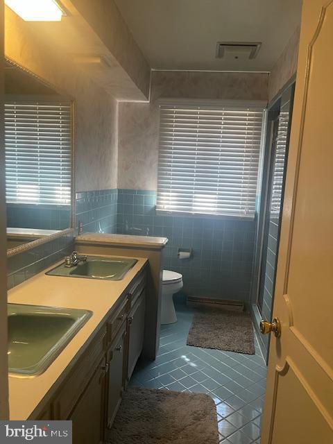 full bath with tile patterned flooring, toilet, tile walls, and a sink