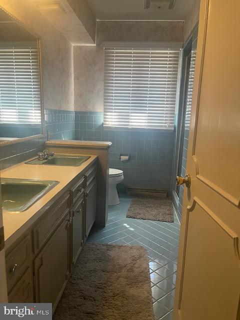 full bath featuring a sink, toilet, a stall shower, and tile patterned flooring