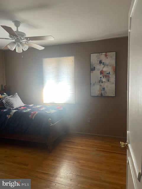 bedroom featuring baseboards, wood finished floors, and a ceiling fan