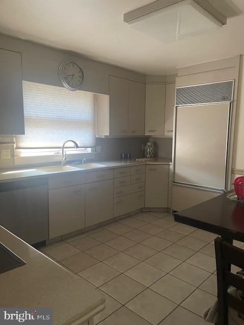 kitchen with a sink, light countertops, light tile patterned floors, and paneled refrigerator