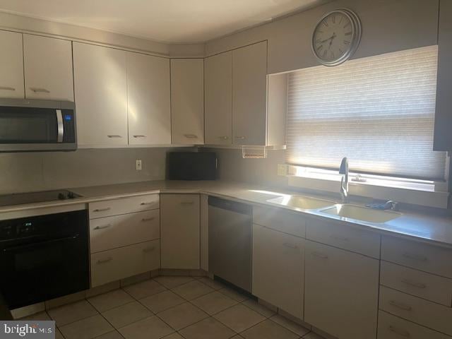 kitchen featuring black appliances, white cabinets, light countertops, and a sink