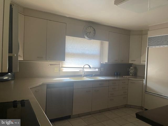 kitchen with light tile patterned floors, white cabinetry, light countertops, and a sink