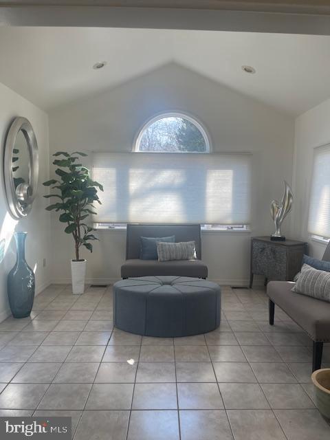 living room with light tile patterned flooring, baseboards, and vaulted ceiling