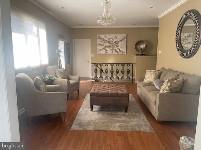 living area with a chandelier, crown molding, and wood finished floors