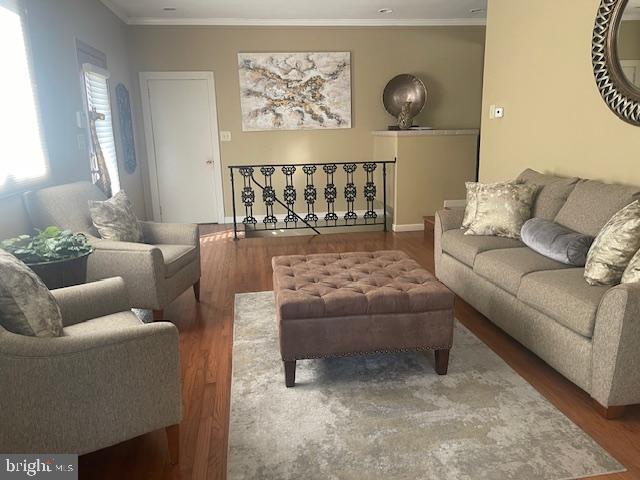 living room with wood finished floors and crown molding