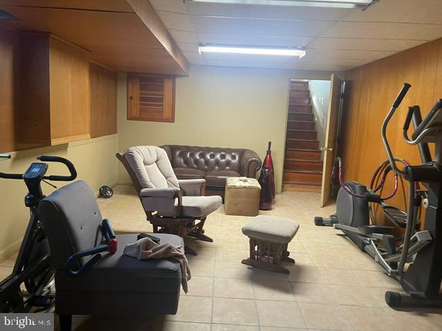 workout room with tile patterned flooring and wood walls