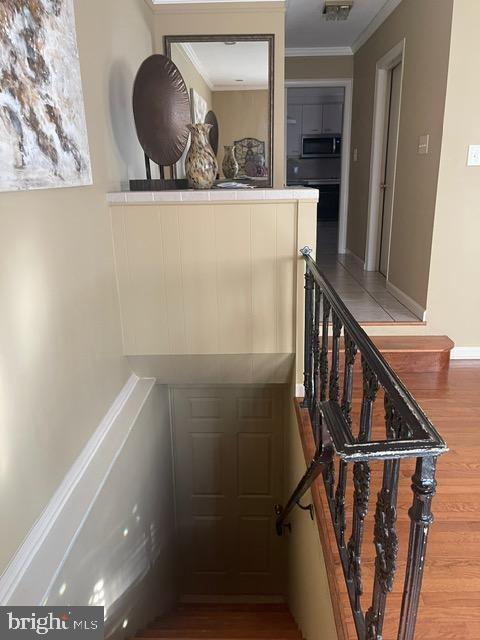 stairs featuring visible vents, wood finished floors, and crown molding