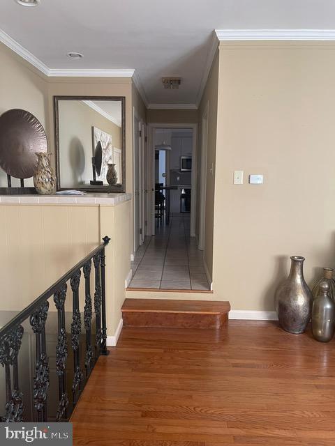 hall with wood finished floors, baseboards, and ornamental molding