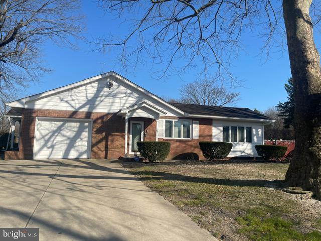 single story home with a front yard, an attached garage, brick siding, and driveway