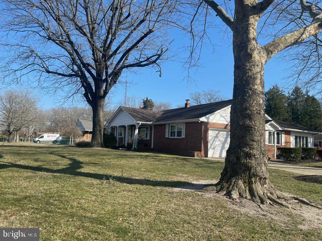 view of home's exterior with an attached garage, a chimney, and a yard