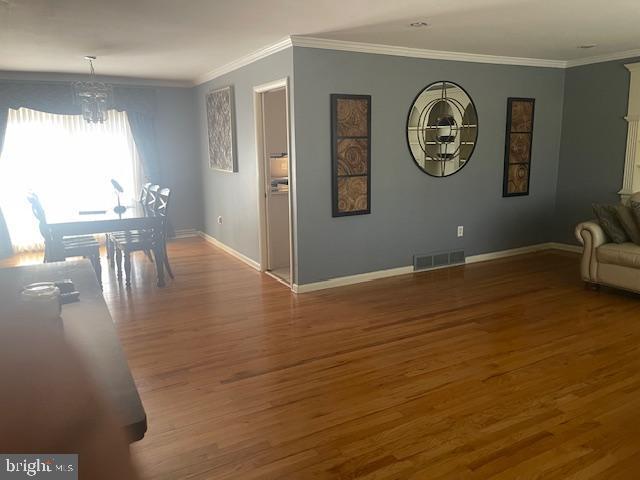 dining room with an inviting chandelier, crown molding, wood finished floors, and visible vents