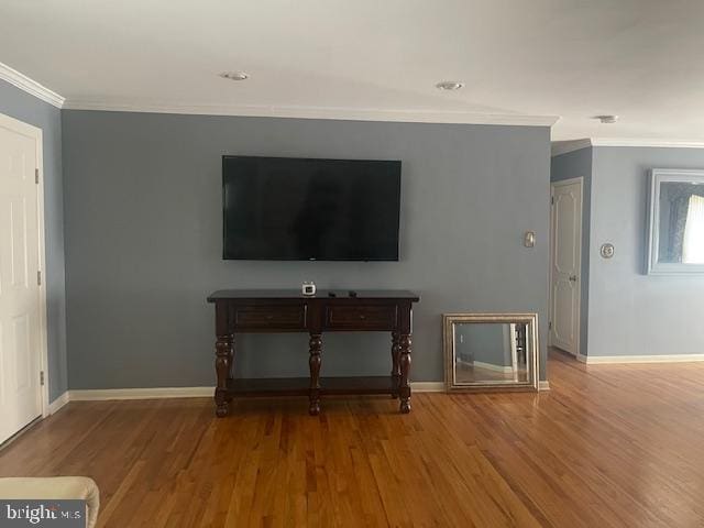 unfurnished living room featuring wood finished floors, baseboards, and ornamental molding