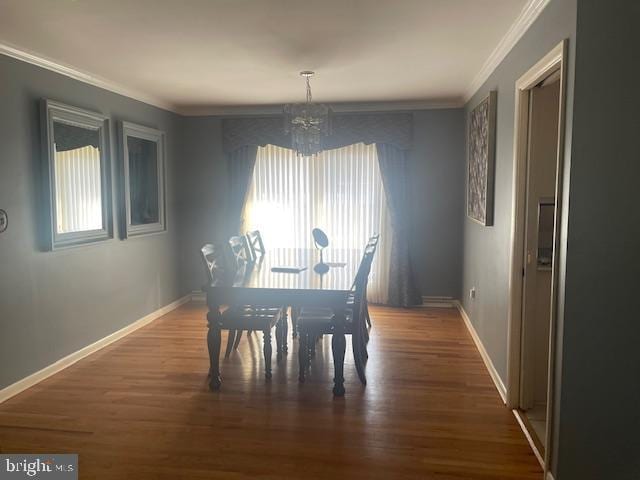 dining room with an inviting chandelier, crown molding, wood finished floors, and baseboards