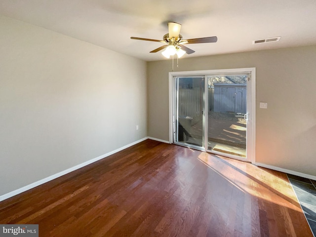 empty room featuring dark wood finished floors, visible vents, baseboards, and ceiling fan