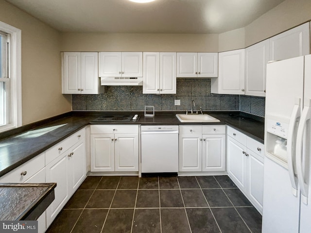 kitchen with white appliances, a sink, under cabinet range hood, white cabinetry, and dark countertops