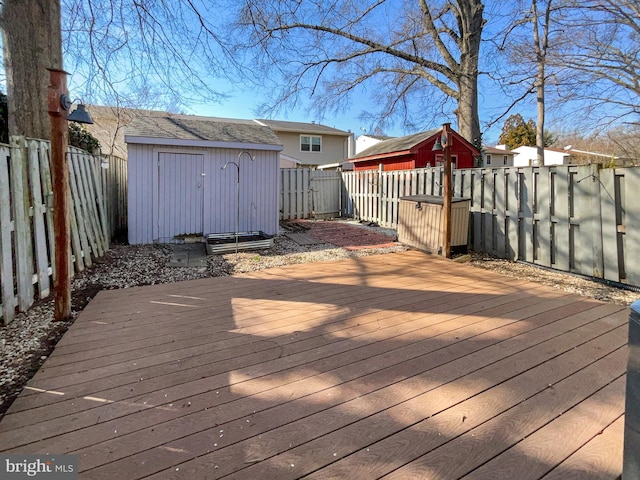 deck with an outdoor structure, a fenced backyard, and a shed